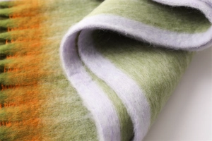 Macro shot of thick faux cashmere scarf featuring green and orange gradient plush fibers