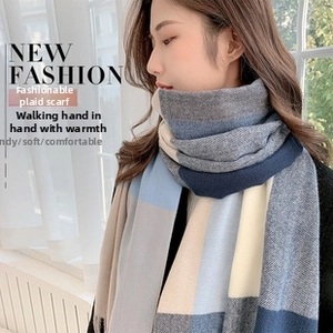 Close-up of a thick checkered cashmere-feel scarf in blue and beige tones worn by a model