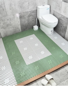 Detail of green and white TPE bath mat with drainage holes and massage texture