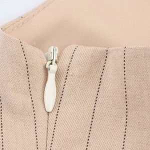 Détail du tissu rayé beige camel avec une fermeture éclair invisible blanche de qualité