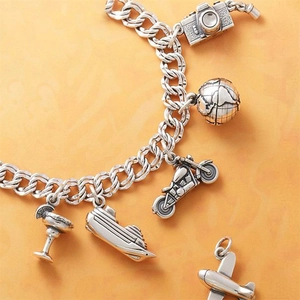 Detailed view of silver charm bracelet featuring camera, globe, and plane travel pendants