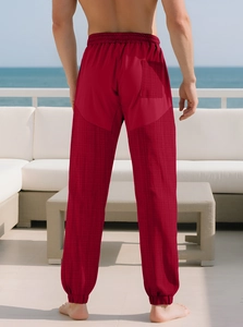 Detail of red joggers with waffle texture panels and elastic cuffs in outdoor beach setting