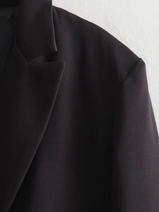 Close-up of black blazer lapel showing high-quality twill fabric texture and stitching
