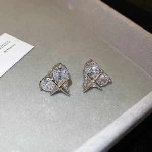 Close-up of heart-shaped zircon ear clips in silver metal on a soft jewelry tray