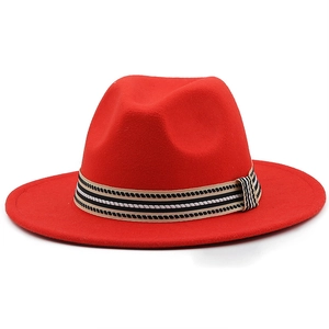 Dettaglio del cappello in lana rossa con fascia a righe tricolore e fibbia dorata elegante