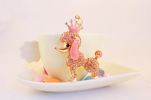 Close-up of golden poodle keychain with pink crown and sparkling champagne rhinestones
