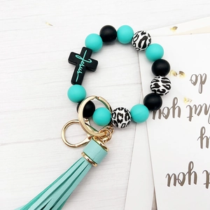 Detail of mint green and leopard silicone bead wristlet with Jesus cross charm and tassel