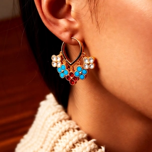 Close-up of vintage 18K gold plated flower tassel hoop earrings worn with white knitwear