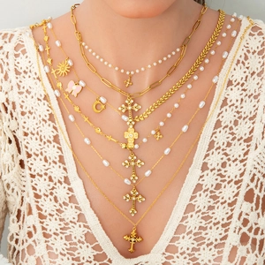 Détail de colliers multicouches dorés avec chaîne de perles et pendentifs croix