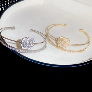 Macro detail of gold and silver double-layer flower bracelets with pavé cubic zirconia