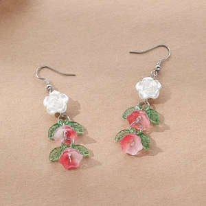 Detail of floral drop earrings with white roses and pink bell-shaped flowers