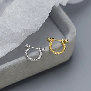 Macro shot of sparkling zircon paved huggie hoop earrings in gold and silver finish