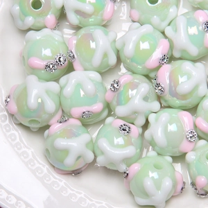 Macro view of light green hand-painted beads with floral patterns and small rhinestones