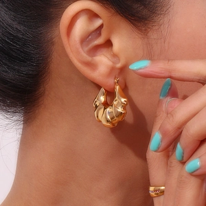 Macro detail of gold chunky twisted croissant hoop earrings and sparkling ring set