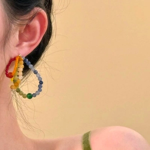 Close-up of a model wearing colorful rainbow beaded hoop earrings for summer