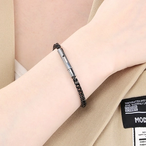 Macro detail of black stainless steel woven chain bracelet with silver clasp on sleeve