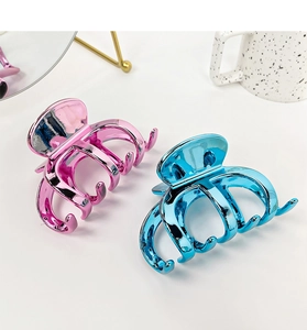 Detail view of large pink and blue metallic hair claw clips on a white background