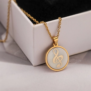 Gros plan d'un collier doré avec pendentif clé de sol sur une boîte à bijoux blanche