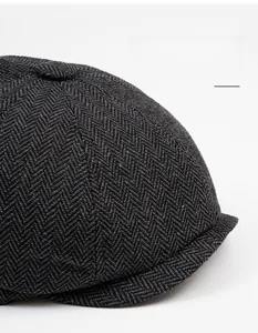 Detailed view of dark grey herringbone texture on a classic newsboy cap with top button