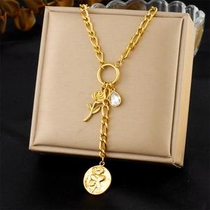 Dettaglio della collana con ciondolo rosa dorata e cristallo su portagioie beige