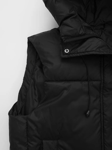 Detail of hooded black puffer vest showing the zipper, metallic snap buttons and quilting