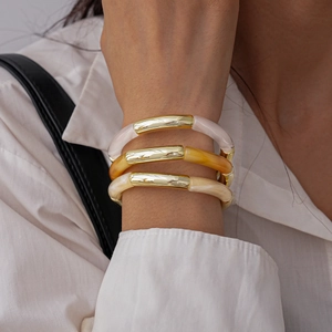 Close-up of three-piece acrylic marble bracelets with gold metal accents on a wrist