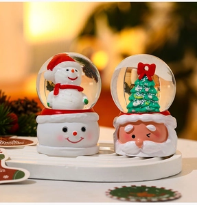 Detailed view of resin Christmas snow globes with snowman and Santa Claus designs