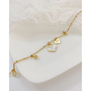 Detail of gold titanium steel bracelet with heart shell pendant and Love engraving