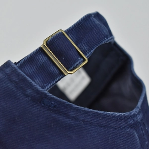 Macro detail of dark blue cotton baseball cap with vintage bronze metal adjustment buckle