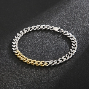 Macro shot of two-tone Cuban chain bracelet showing silver and gold textured links
