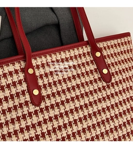 Detail of red tweed houndstooth tote showing golden rivets and leather handle