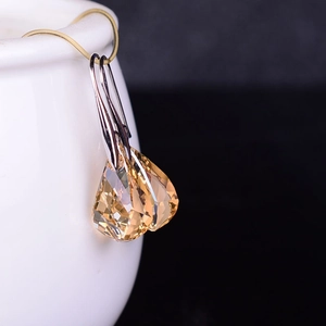Champagne crystal teardrop earrings with silver hooks shown on a white ceramic cup