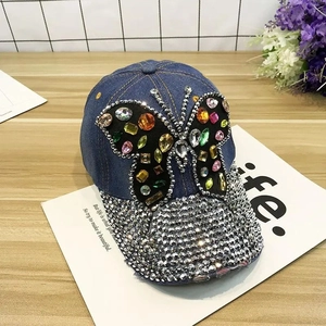Close-up of denim baseball cap featuring colorful crystal butterfly and rhinestone brim
