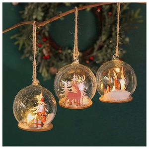 Hanging glowing Christmas glass balls with Santa and reindeer scenes on warm LED wooden base