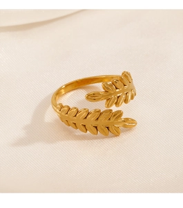 Detailed close-up of golden leaf-shaped open ring on soft white satin fabric