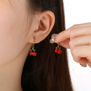 Close-up of sweet red cherry earrings with green leaves on gold metal hoops for women