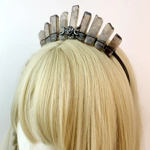 Detail of smoky crystal crown with metallic pentagram and moon on golden hair