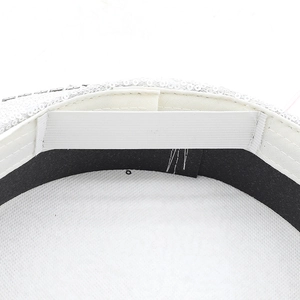 Détail de la casquette à paillettes blanches montrant le bandeau noir et le lien élastique