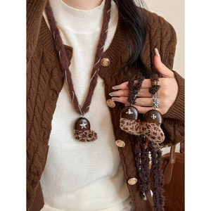 Dettaglio della collana a cuore in peluche leopardato con croce e ciondolo a globo