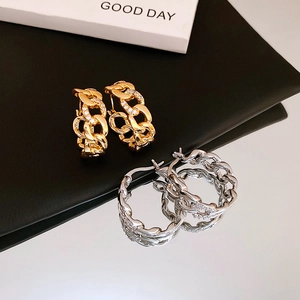 Close-up of interlocking gold-plated and silver chain earrings with sparkling zircons