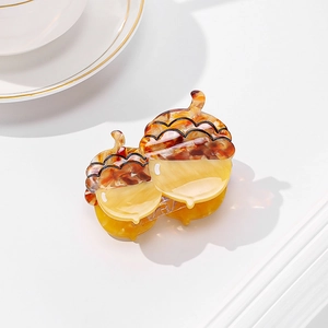 Chic brown and yellow acetate food-shaped hair claw clip on a minimalist white table