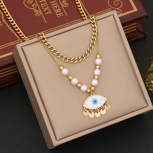 Detail of double-layer gold necklace with pearls and evil eye charm on jewelry box