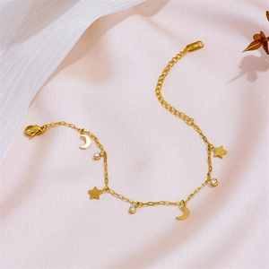 Golden stainless steel star and moon charm bracelet with crystals on pink silk background