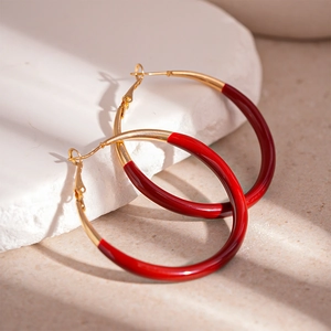 Detail of red enamel and gold circle hoop earring on white stone with shadow effect