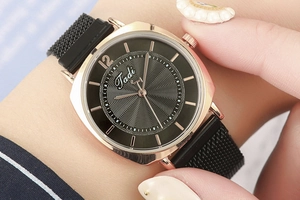 Gros plan d'une montre à quartz or rose avec cadran noir soleil et bracelet magnétique