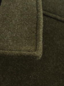 Détail macro du tissu en tweed de laine vert olive montrant la texture épaisse