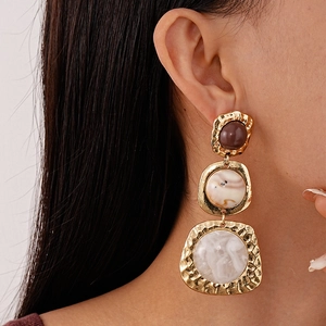 Close-up of vintage resin geometric earrings with gold irregular frames and marble texture