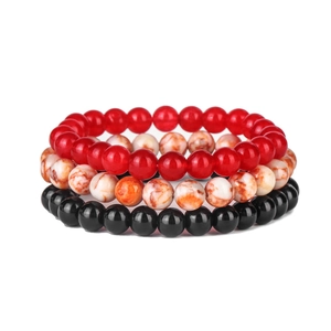 Macro detail of three-piece beaded stretch bracelets with red, white, and black agate stones