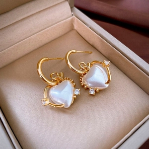 Macro detail of gold hoop earrings with white heart pendant and zircon stones
