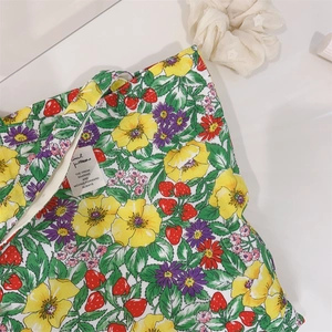 Dettaglio ravvicinato del tessuto di cotone con stampa di fiori e fragole e cartellino